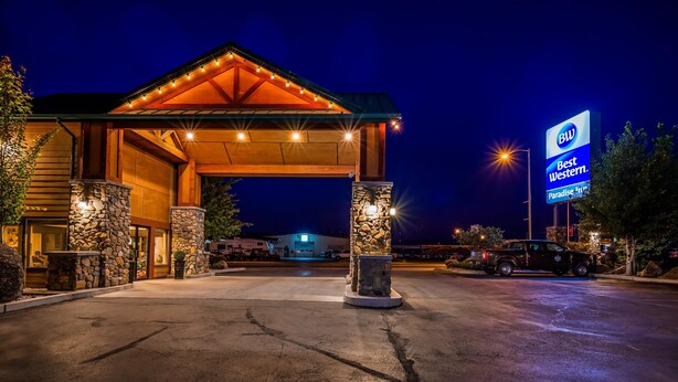 A hotel entrance with a covered walkway, stone pillars, and a large sign advertising the hotel. - Best Western Paradise Inn (Dillon)