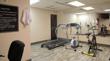 Gimnasio con equipo de ejercicio, un espejo y un cartel que indica que es solo para huéspedes registrados.