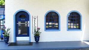 A building with a blue door labeled "Office" and a "WELCOME" sign. There are three arched windows and two potted plants on the sidewalk. - Days Inn by Wyndham Harriman (Harriman)