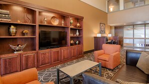 A hotel lobby with a wooden entertainment area, seating, a desk, and a view through large windows. - Best Western Lapeer Inn (Lapeer)