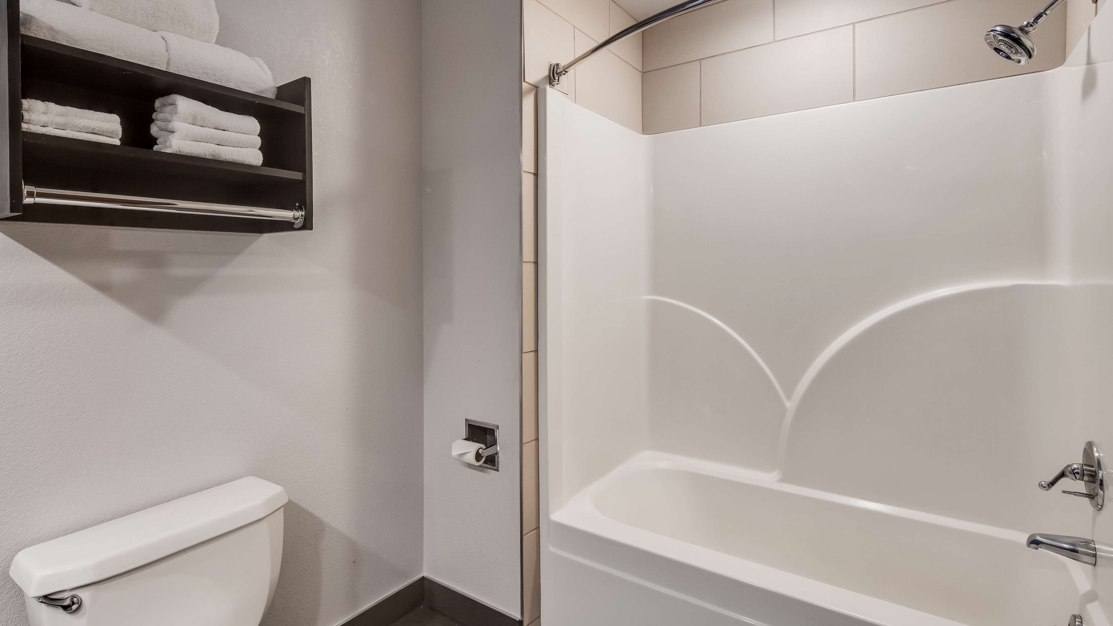 Une salle de bain équipée de toilettes, d’une douche et d’une étagère où sont rangées les serviettes.