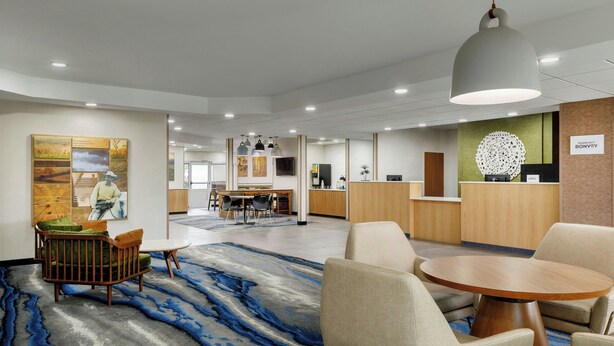 Eine Hotelhalle mit Empfangsschalter, Sitzgelegenheiten und Kunstwerken an den Wänden.