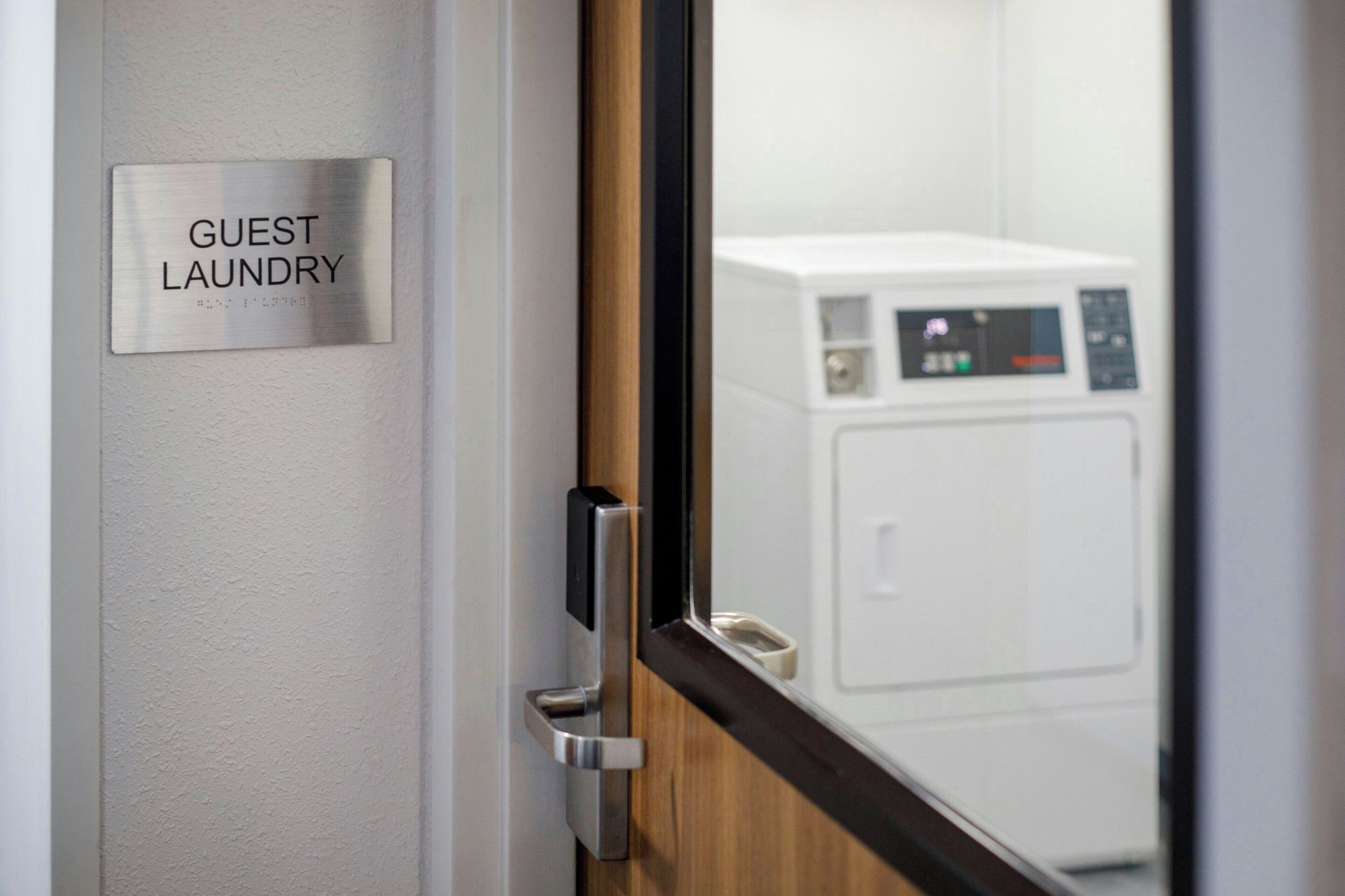 A door with a sign reading 'GUEST LAUNDRY' and a view of a white washing machine.
