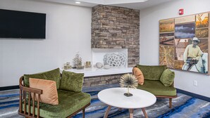 Ein modernes Wohnzimmer mit zwei grünen Sofas, einem weißen Couchtisch und einer Wand mit Steinverkleidung.