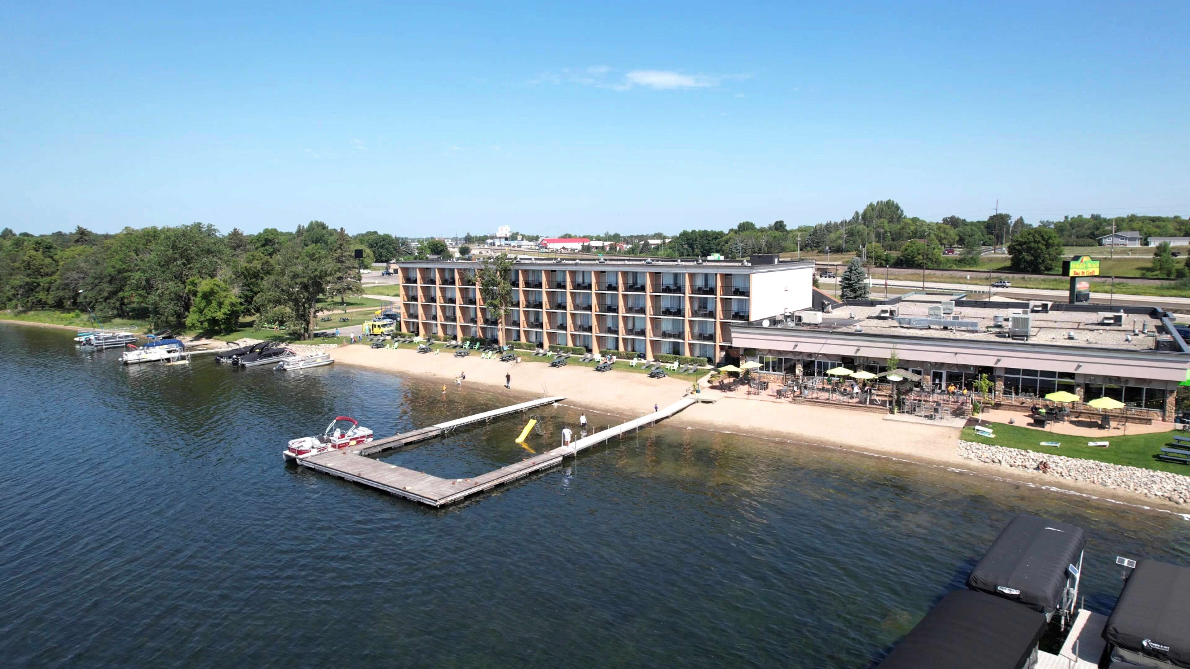 A waterfront hotel with a dock, outdoor seating, and a large building with multiple floors.