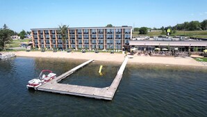 Um hotel à beira-mar com um cais, área de piscina e um edifício com várias varandas.
