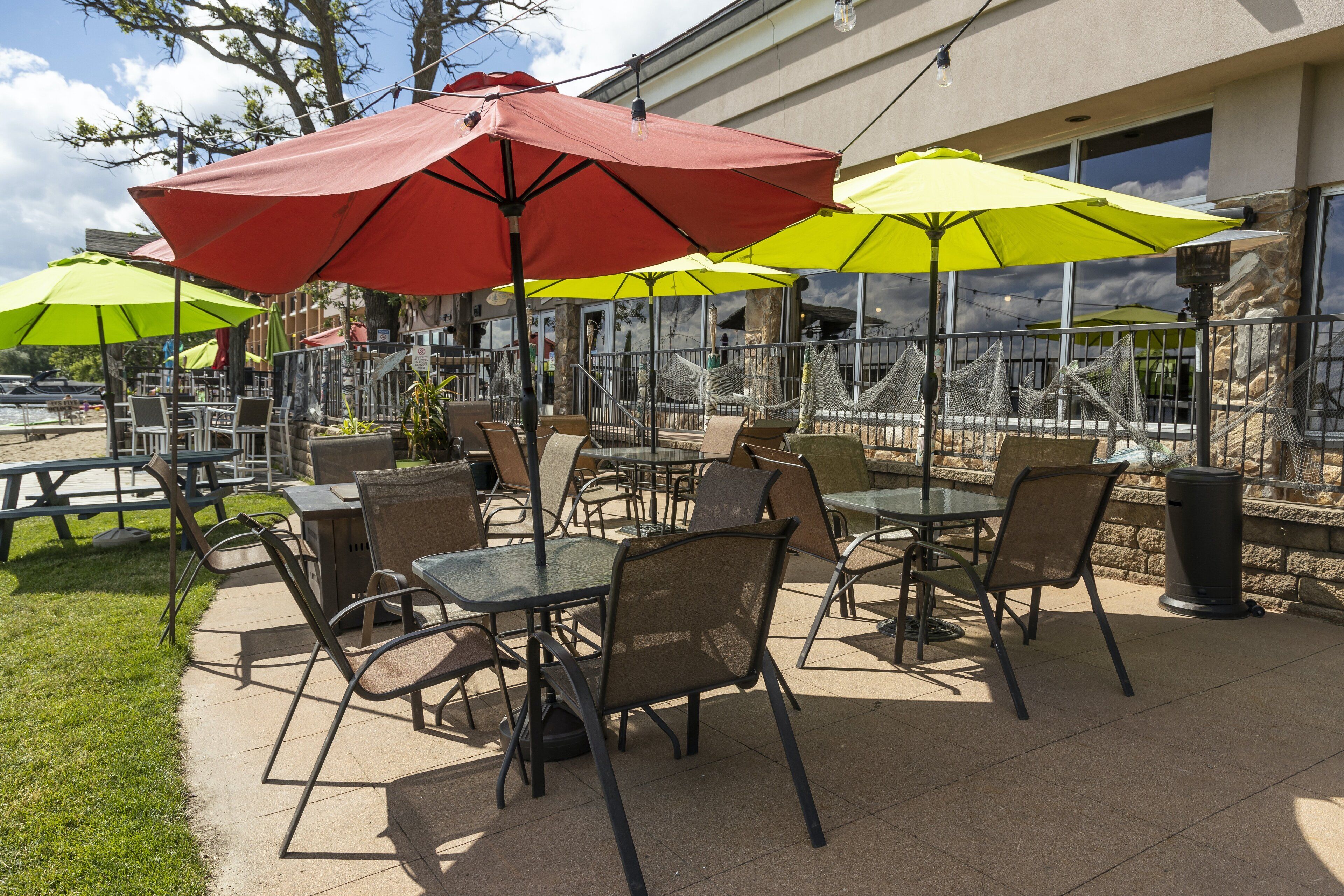 An outdoor patio with tables and chairs, surrounded by umbrellas.