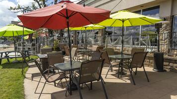 An outdoor patio with tables and chairs, surrounded by umbrellas.