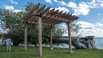 Et pergola af træ med udsigt over en sø og både i baggrunden.