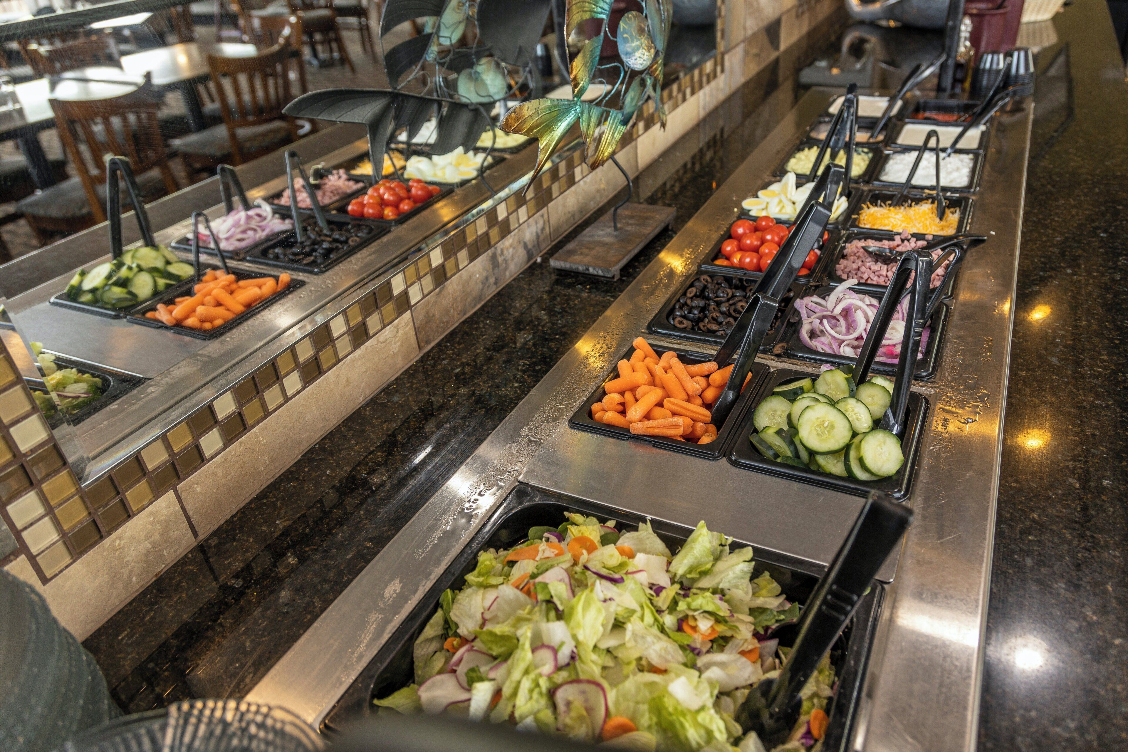 A buffet with various food options including vegetables, meats, and salads.