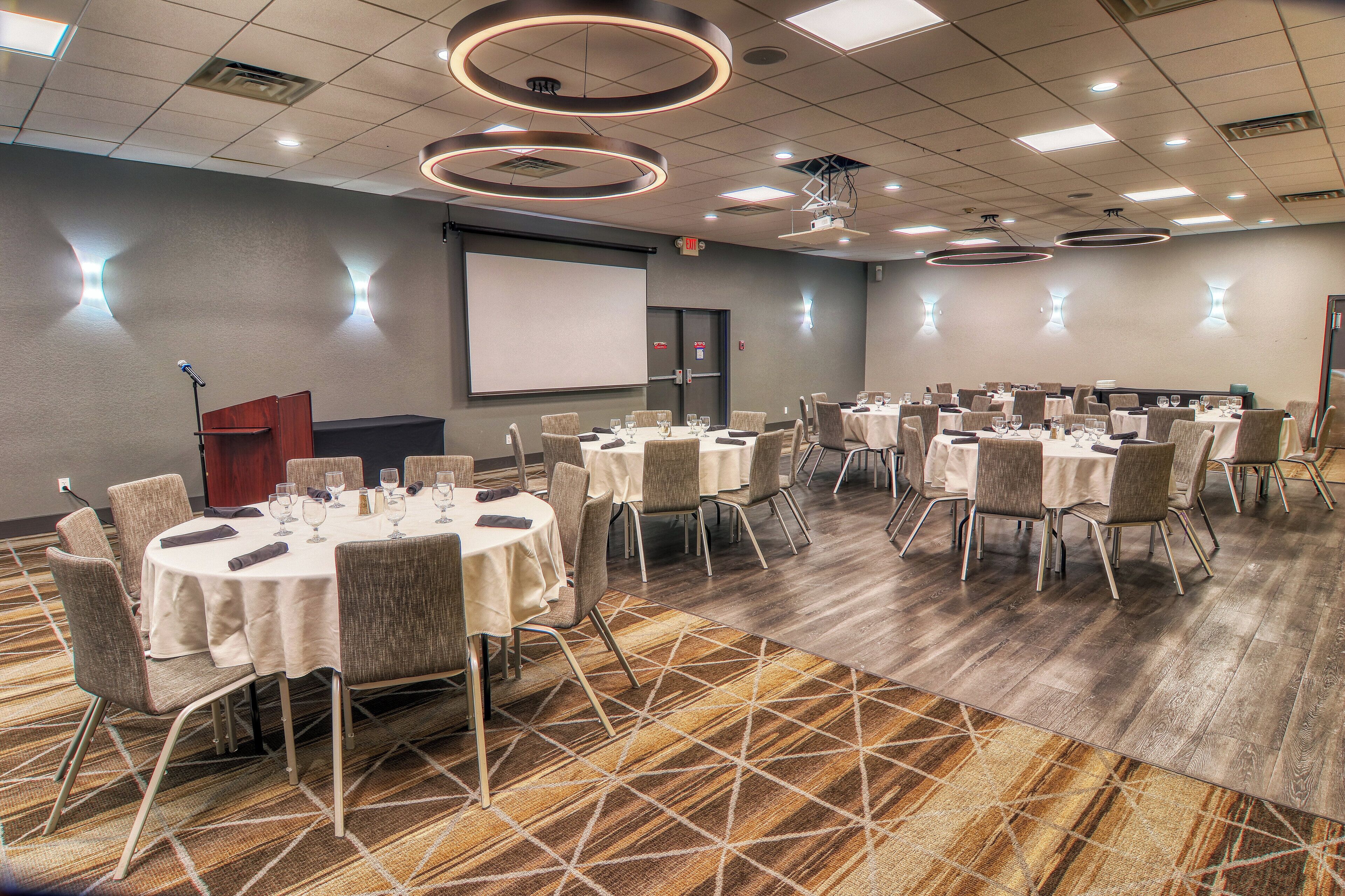 A conference room with round tables, chairs, and a podium.