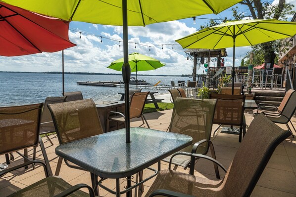 Outdoor seating with tables and chairs, umbrellas, and a view of the water.