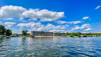 Un hotel frente al agua con un edificio moderno, barcos amarrados y un cielo azul despejado.