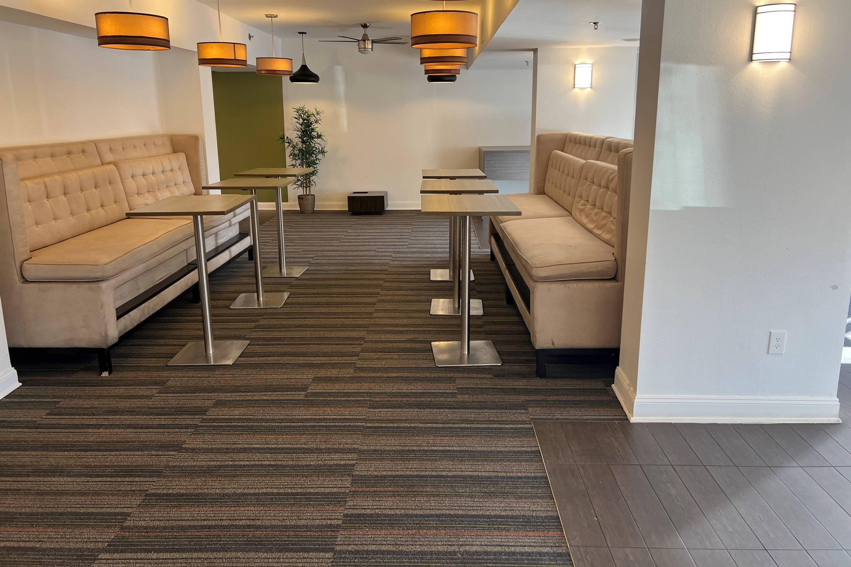 A modern hotel lobby with a seating area, tables, and a ceiling fan.