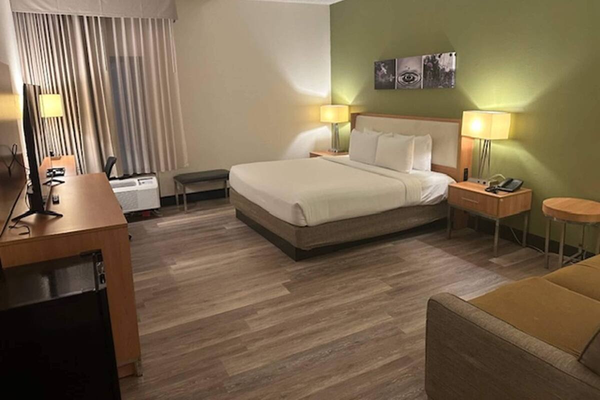 Habitació d'hotel amb un llit, taules de nit, un escriptori, una cadira i un sofà.