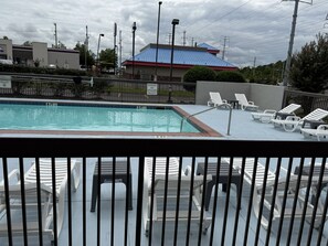 A swimming pool with lounge chairs and a lifeguard warning sign.