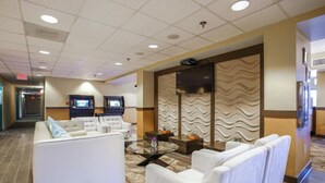 Eine Hotelhalle mit Sitzgelegenheiten, einem Fernseher und einer Wand mit Muster.