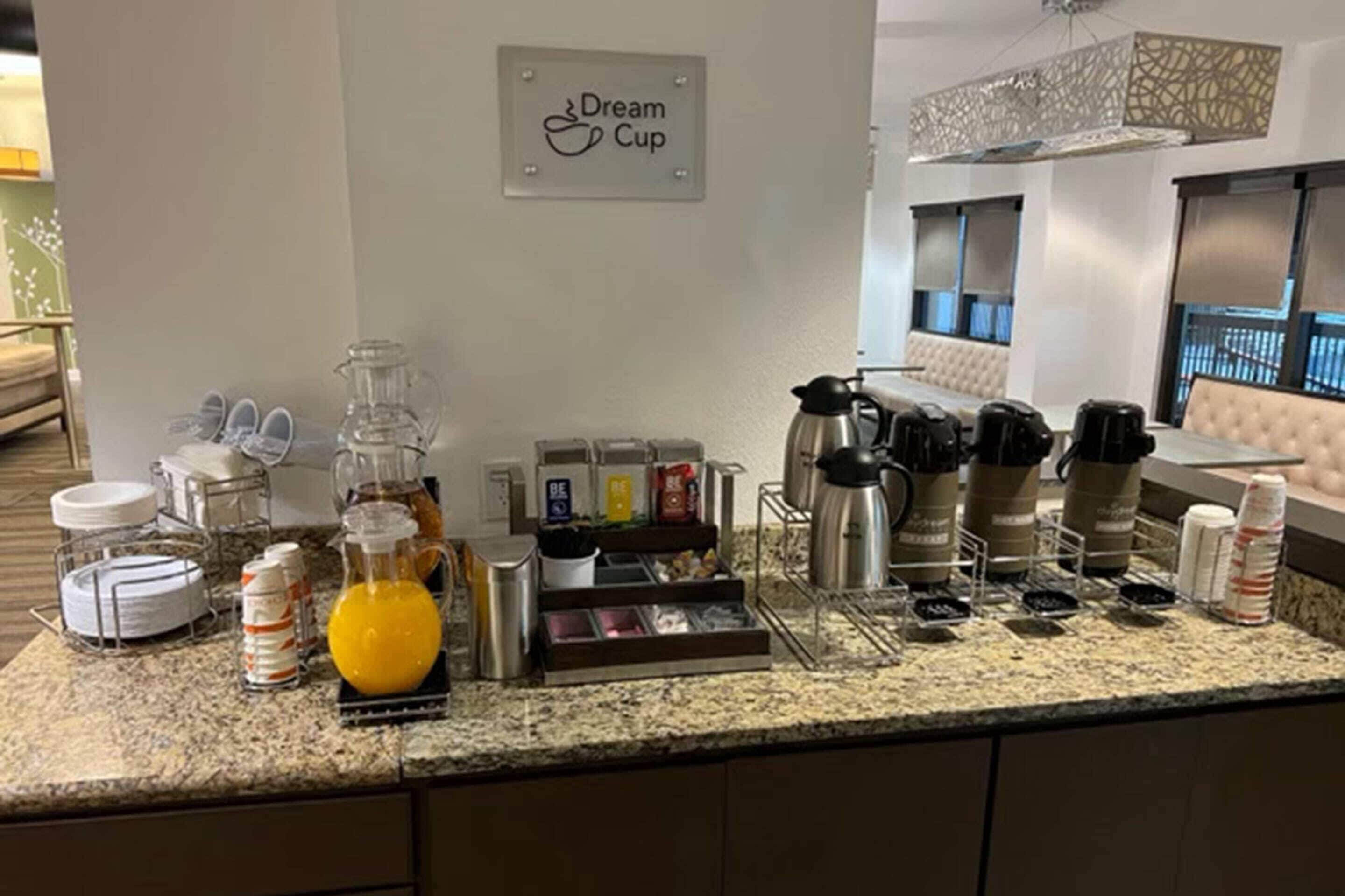Una cuina d'hotel amb un racó de cafè, un cartell que diu 'Dream Cup' i diversos electrodomèstics de cuina.