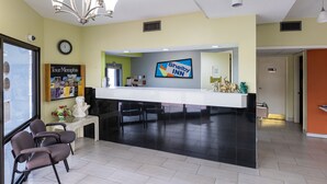 Et hotelreceptionsområde med et Shelby Inn skilt, et ur, en 'Tour Memphis' brochure og en receptionsdisk.