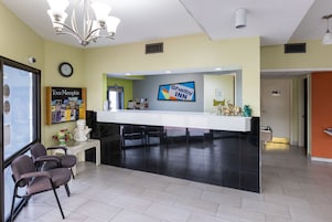 A hotel reception area with a Shelby Inn sign, a clock, a 'Tour Memphis' brochure, and a reception desk.