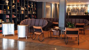 A modern lobby with a large bookshelf, comfortable seating areas, and a reception desk labeled "CONFERENCE DESK". - Radisson Blu Arlandia Hotel (Arlanda)