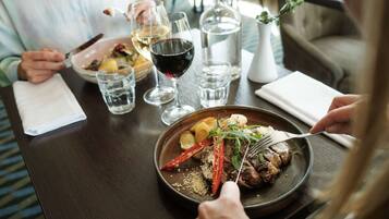 Una mesa de comedor con un plato de comida, copas de vino y una botella de agua.