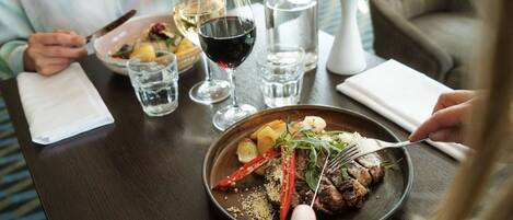 Une table à manger avec une assiette de nourriture, des verres de vin et une bouteille d’eau.