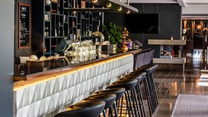A modern bar area with a counter, bar stools, and a variety of decorative items. - Radisson Blu Arlandia Hotel (Arlanda)