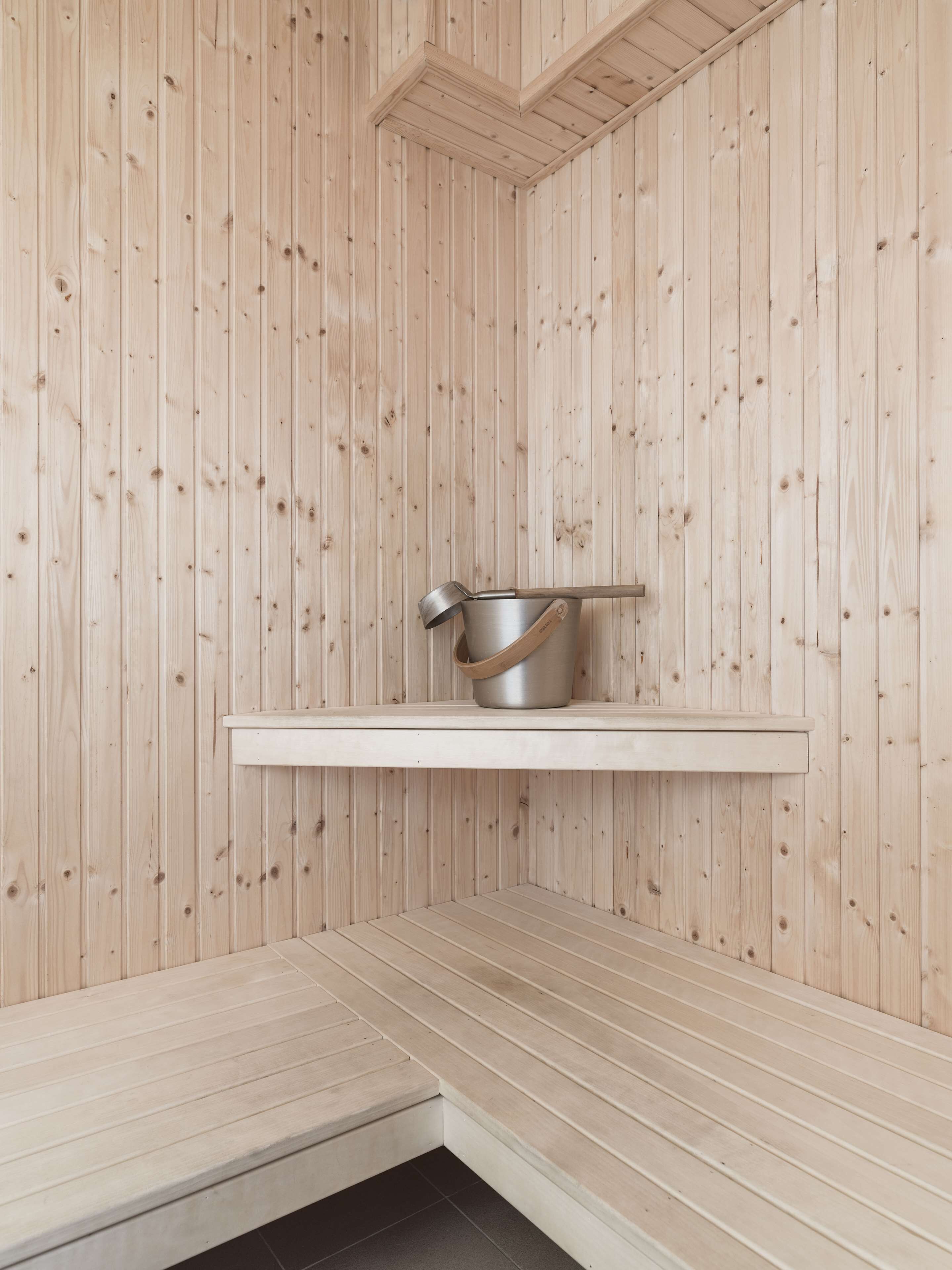 Una sauna con pareti in legno, uno scaffale con una pentola e una panca.