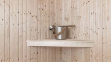 Una sauna con pareti in legno, uno scaffale con una pentola e una panca.