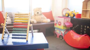 Ein Holztisch mit einem Abakus, einem Teddybären und einem Spielzeugauto.