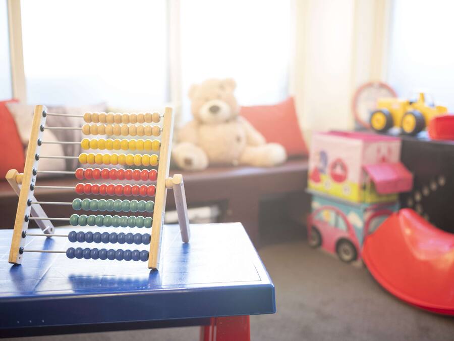 Ein Holztisch mit einem Abakus, einem Teddybären und einem Spielzeugauto.