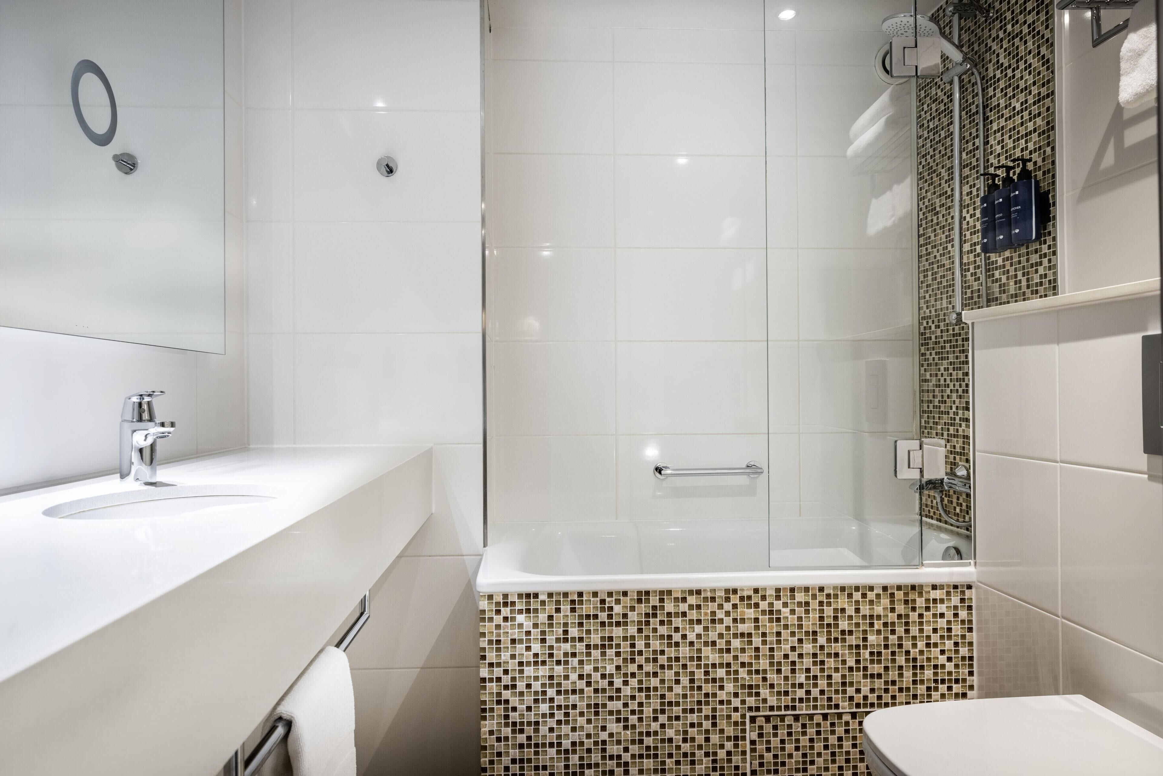 A modern bathroom with a glass-enclosed shower, a white sink, and a toilet.