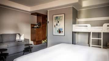 A hotel room with a bed, a sofa, a small table, a coffee machine, and a bunk bed.