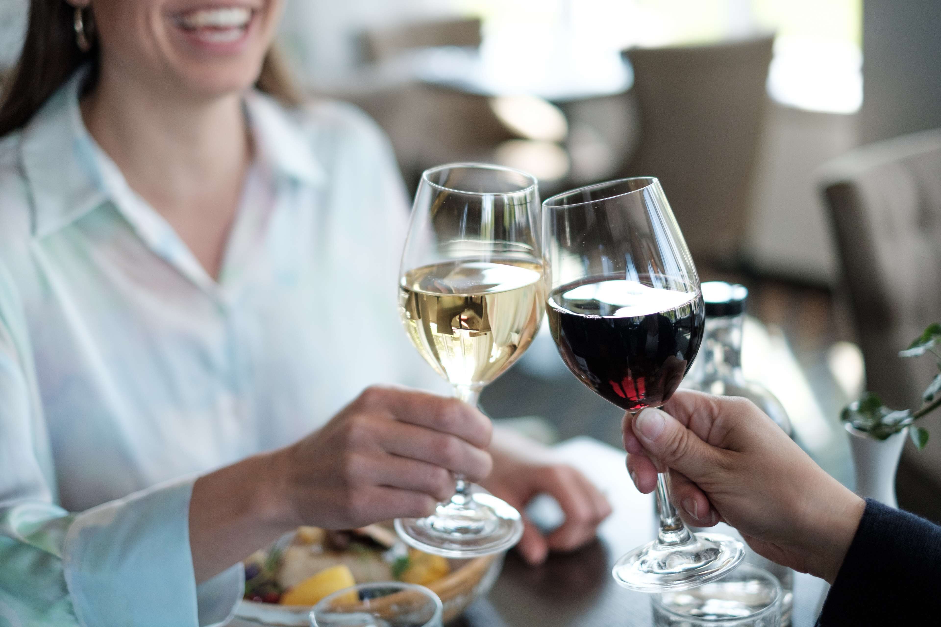 A person holding a wine glass with a white wine and another with red wine.