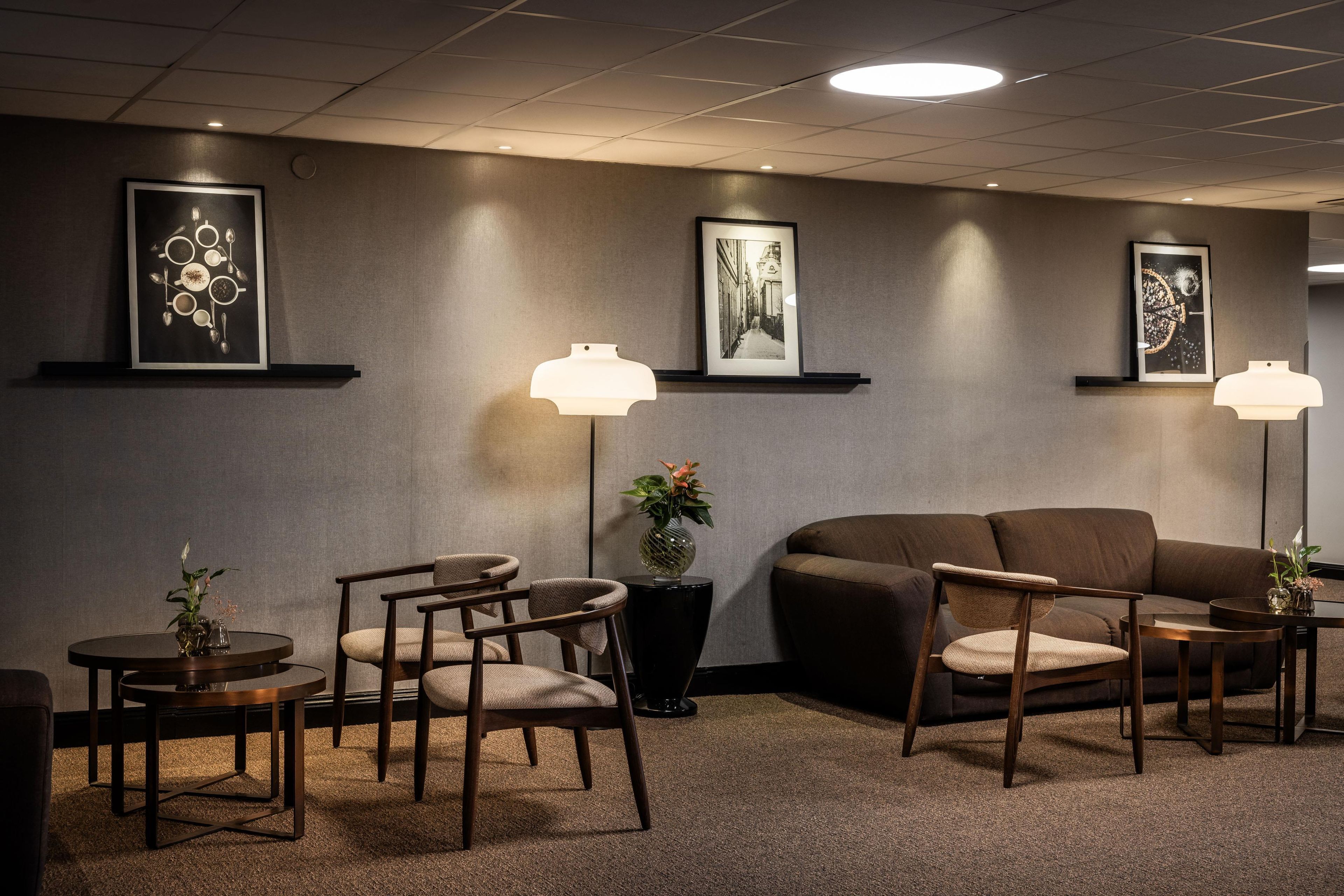 A modern waiting area with a sofa, chairs, and artwork on the walls.