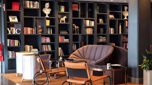 A modern library with bookshelves, a comfortable armchair, and a small table. - Radisson Blu Arlandia Hotel (Arlanda)