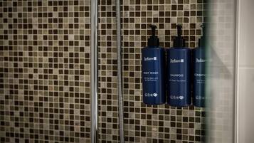 Un bagno con una parete piastrellata e tre flaconi di prodotti da bagno Radisson: bagnoschiuma, shampoo e balsamo.