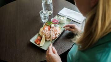 Una persona sta cenando a un tavolo rotondo, con un piatto di cibo, un bicchiere d'acqua e una bottiglia d'acqua.