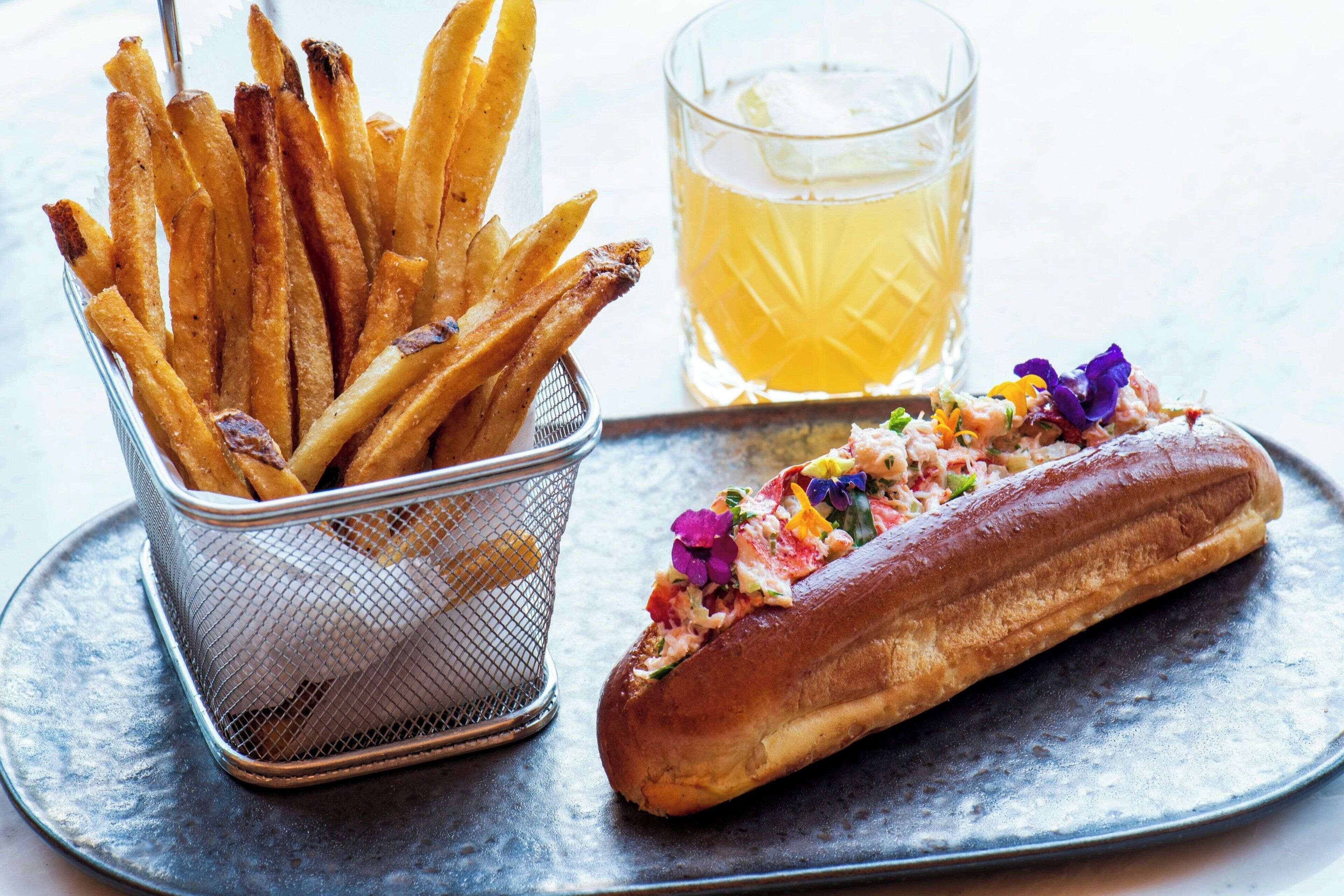 A basket of fries, a glass of beer, and a sandwich on a tray.