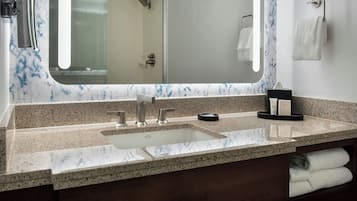 A bathroom with a granite countertop sink, a large mirror, and a towel rack.