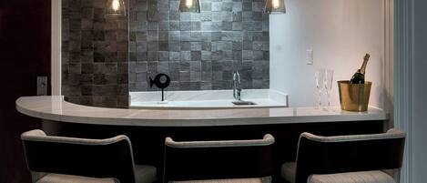 A modern kitchen with a curved island, two pendant lights, and a wine bottle in a gold bucket.