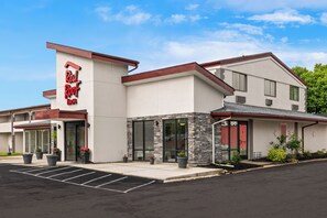 A Red Roof Inn with a modern design, featuring a large glass entrance, stone accents, and a parking lot.