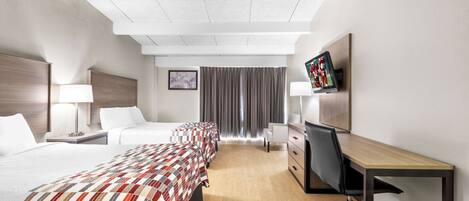 A hotel room with a large bed, a desk with a chair, a TV, and a window with curtains.