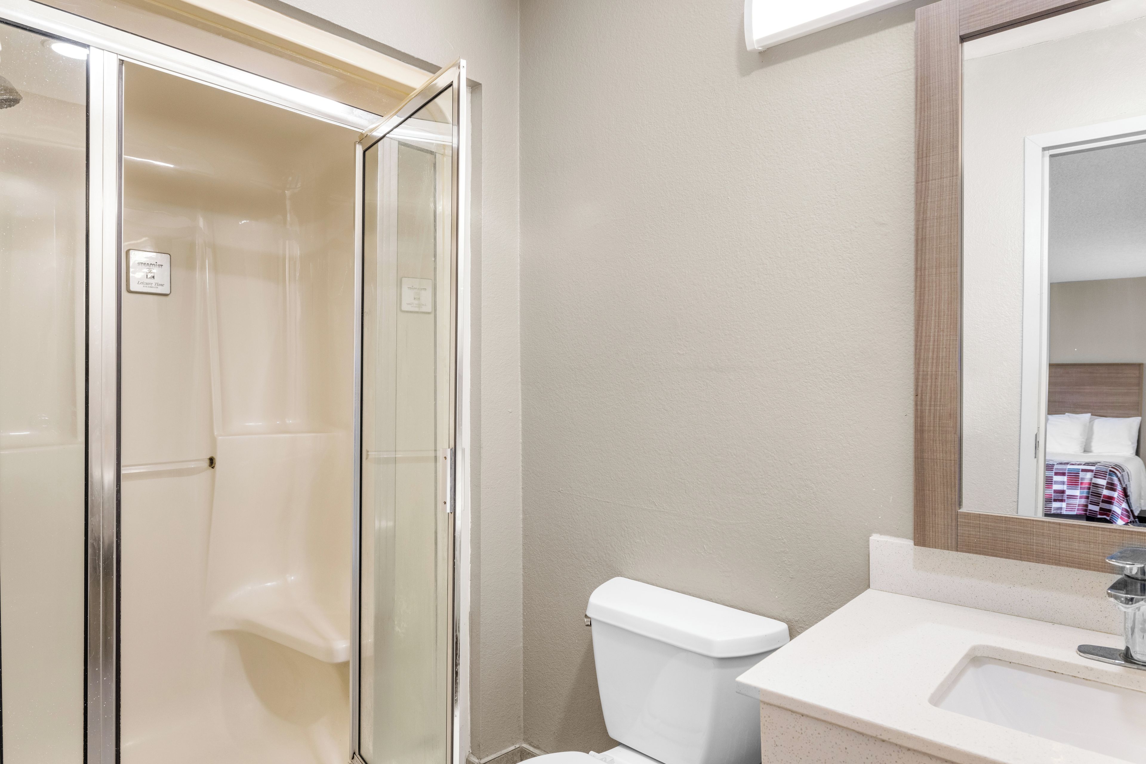 Un baño con cabina de ducha de vidrio, inodoro y lavabo con espejo.
