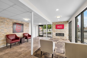 A Red Roof Inn lobby with a stone wall, leather chairs, a fireplace, and a sign indicating all rooms have Wi-Fi. - Red Roof Inn Niagara Falls (Niagara Falls)