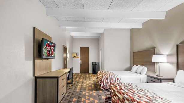 A hotel room with a bed, a desk, a television, a wardrobe, and a patterned carpet. - Red Roof Inn Niagara Falls (Niagara Falls)
