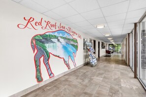 A corridor with a mural of Niagara Falls and Red Roof Inn signage.