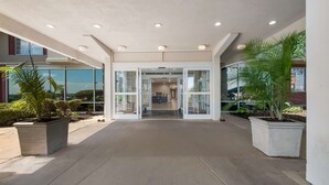 A spacious entrance area with a modern design, featuring a glass door entrance, potted plants, and a concrete floor. - Country Inn & Suites by Radisson, Fredericksburg South (I-95), VA (Fredericksburg)
