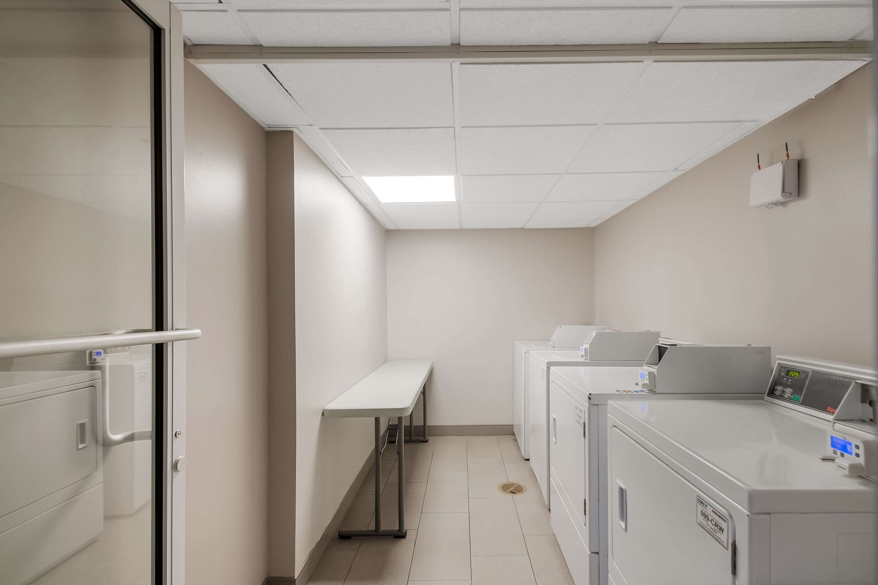 Una sala de lavandería con banco, lavadoras y panel de control.